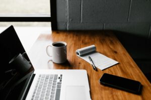 Laptop mit Kaffeetasse, Notizblock und Smartphone auf Holztisch. Symbolbild für PKV-Tarifvergleich 2026 für Selbstständige